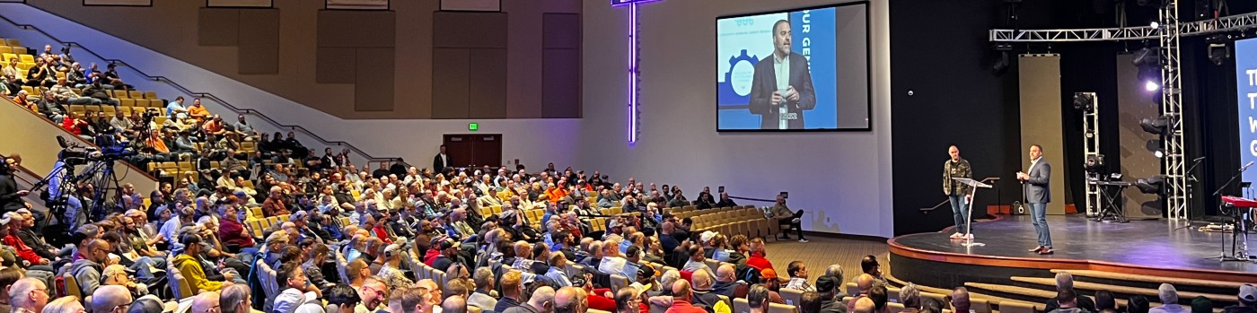 Dom Zappia speaking on stage to a large audience